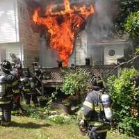 <p>Flames are visible as Norwalk firefighters arrive at the home on Riverside Avenue on Thursday.</p>