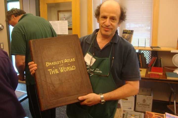 Paul Weissman displays an 1889 atlas on sale at the Mark Twain Library&#x27;s annual book fair at the Redding Community Center.