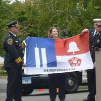 <p>Diane Wells, right, regent of the Hannah Benedict Carter chapter of the Daughters of the American Revolution presents a flag to New Canaan first responders. Each part of the flag represents the three areas involved in the 9/11 attacks.</p>