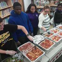 <p>Students and a PTA member prepare to serve food.</p>