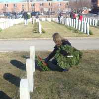 <p>Darien First Selectman Jayme Stevenson lays several wreaths on the graves of veterans.</p>