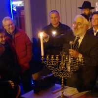 <p>Rabbi Yehoshua Hecht of Beth Israel of Westport/Norwalk lights candles on the menorah, assisted by Chief Thomas Kulhawik and Stew Leonard Jr.</p>