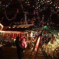 <p>Families take a stroll through the Christmas Village on the Settis front lawn, admiring all the hand-made displays.</p>