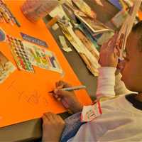 <p>Seven-year-old Marc Rowe works on his message in honor of MLK Day.</p>