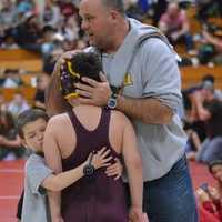 <p>Tournament champion Drew Falla is greeted by his father and assistant coach Pete and fellow Mad Bull and brother, Colin, after winning a gold medal. </p>