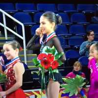 <p>The girls hold up their medals on the on-ice podium. Emilia is at the far left. </p>