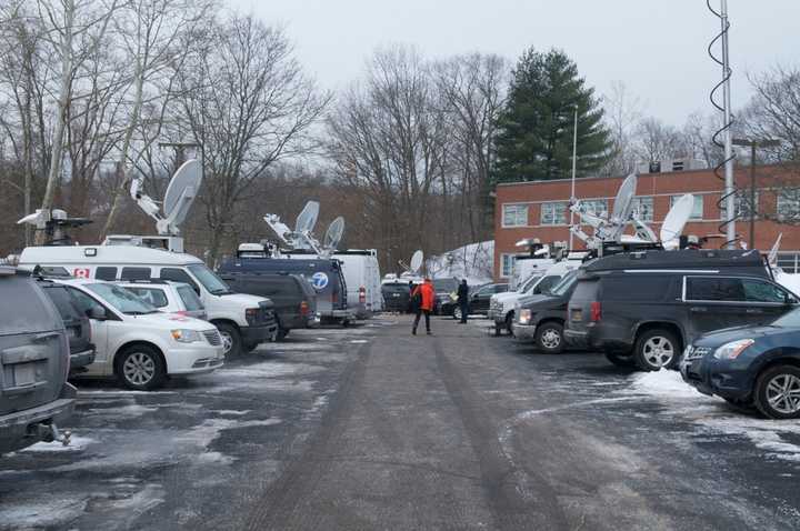 Satellite trucks from TV stations fill the parking lot. 