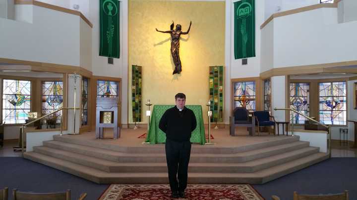 The Rev. Bret Stockdale, S.J., stands in front of the alter at Egan Chapel on Fairfield University&#x27;s Campus.