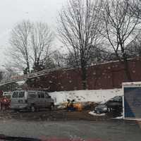 <p>An aerial ladder is deployed on the Rennell Drive side of building to provide access and power tools for roof operations over obstructions. Photo was taken after the fire was extinguished. </p>