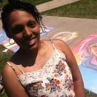 <p>Sasha Cubero, 20, from Bridgeport, a Fine Arts student stands beside her portraiture at the Sidewalk Art Festival.</p>