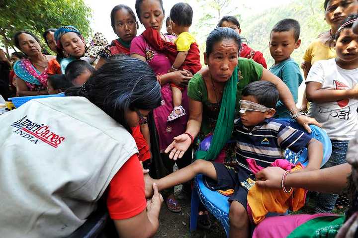 Dr. Swati Jha of AmeriCares treats a 7-year-old earthquake survivors infected wounds during a medical camp in Arughat, in Gorkha District.