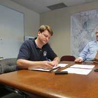 <p>Mamaroneck Village Manager Richard Slingerland, left, and Assistant Village Manager Dan Sarnoff sit at Town Hall, where a FEMA flood map of Mamaroneck stays on the wall. </p>