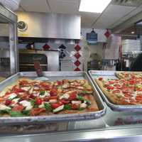 <p>Rudy mans the counter, and displays some of Wednesday&#x27;s specialty slices at Broadway Pizzeria.</p>