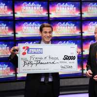 <p>CNN Anchor John Berman accepts a ceremonial check from Alex Trebek, host of Celebrity Jeopardy! </p>