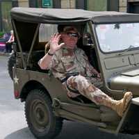 <p>A veteran waves from a jeep.</p>