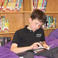 <p>Student checks out a book at the Scholastic Book Fair.</p>