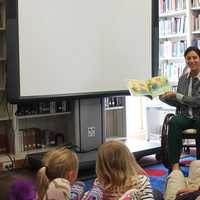 <p>Students enjoy listening to a book read to them at the fair.</p>