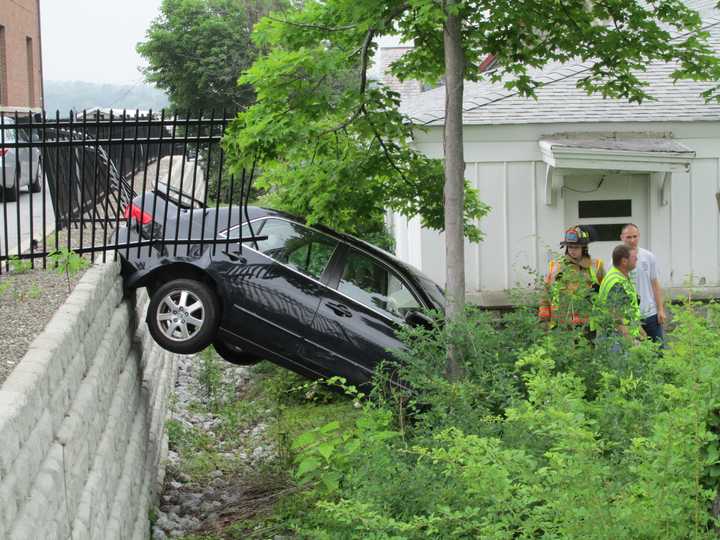 The late-model car hangs precariously off the library wall.