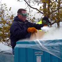 <p>A Con Edison worker scoops dry ice into a bag to distribute to customers without power Wednesday at Empire City Casino.</p>