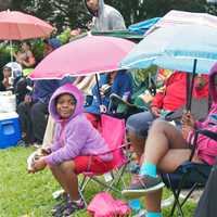 <p>Spectators peek out from under umbrellas at Sunday&#x27;s parade.</p>