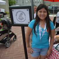 <p>A girl poses in front of the tent for Brewster Pastry at the Danbury Farmers Market. </p>