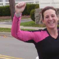 <p>Carolyn Wolfe of Danbury raises her arms as she nears the completion of her 26.2 mile run on Saturday.</p>