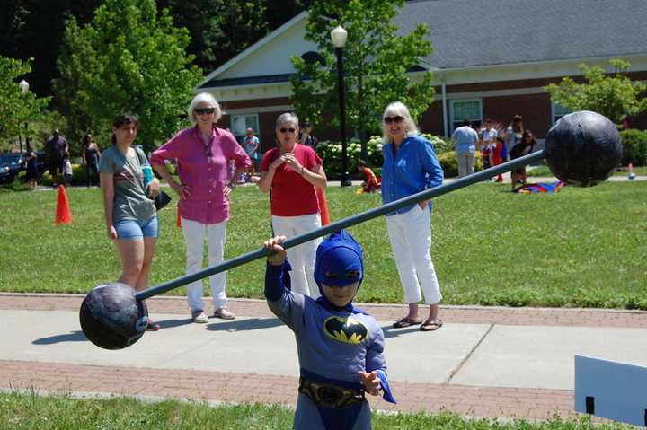 Batman lifts a barbell with ease.