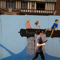 <p>A pedestrian passes by a depiction of the cannons at Compo Beach in Westport. </p>