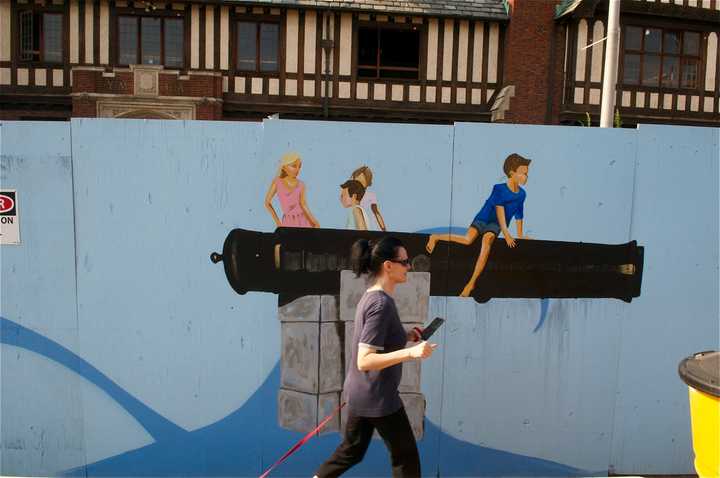 A pedestrian passes by a depiction of the cannons at Compo Beach in Westport. 