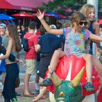 <p>Three young girls pose for a photo on one of the many dinosaurs around Stamford, as part of one of the street art project.</p>