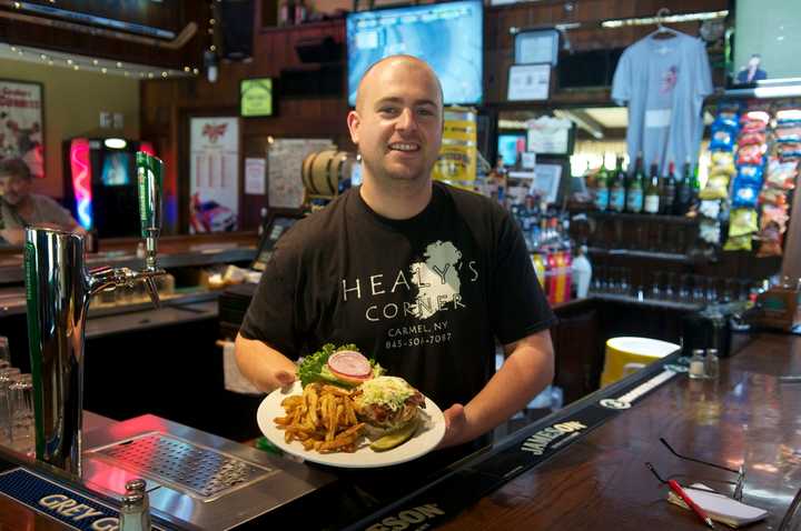 Owner Ryan Healy of Healy&#x27;s Corner serves up one of his Bog Boy Burgers. The 10-ounce patty is topped with three cheeses, bacon, caramelized onions, and coleslaw.