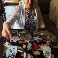 <p>Beth Cohen with photos of her clients over the years.</p>