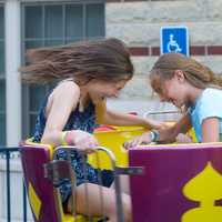 <p>Two girls hold on as they spin in the &#x27;Tea Cups&#x27; ride.</p>