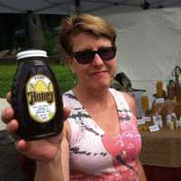 <p>Beekeeper Patty Heyl, of Redding, holds up a bottle of honey at the Wilton sidewalk sale.</p>