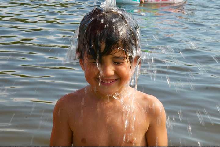 Hudson Meza, of Lake Lincolndale, gets a cool bucket of water dumped on his head Sunday.