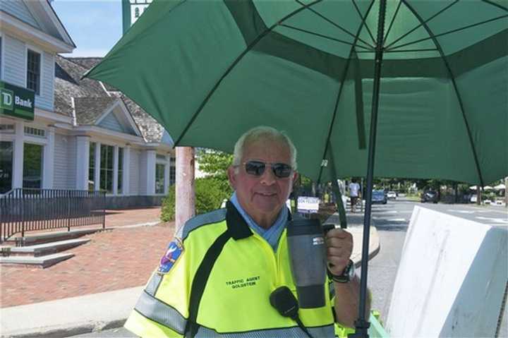 A Westport traffic agent beats the heat with water and an umbrella Sunday. 