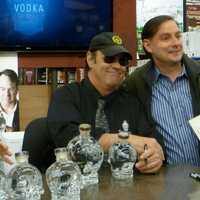 <p>Actor Dan Aykroyd poses for a picture with a fan and signs a bottle of his Crystal Head vodka.</p>