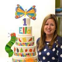 <p>Renata Papadopoulos, owner of Lovely Cakes in Stratford, stands by a masterpiece cake she created for a child&#x27;s first birthday. </p>