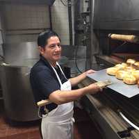 <p>Salvatore Sarmiento pulls a batch of bagels out of the oven at Bagel Train in Suffern.</p>