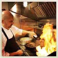 <p>Chef Germano Minin fires up a dish at recently-opened The Village Tavern in Ridgefield.</p>