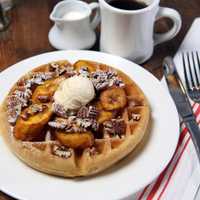 <p>Comfort food like this plate of waffles topped with bananas and walnuts is highlighted in the menu at Judys Bar + Kitchen in Stamford.</p>