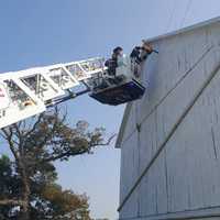 <p>Firefighters cutting out the side wall to access the rafters and free the man.&nbsp;</p>