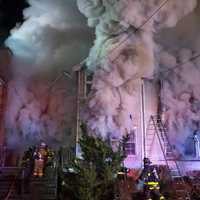 <p>Smoke billows from the home as firefighters put out the flames. </p>