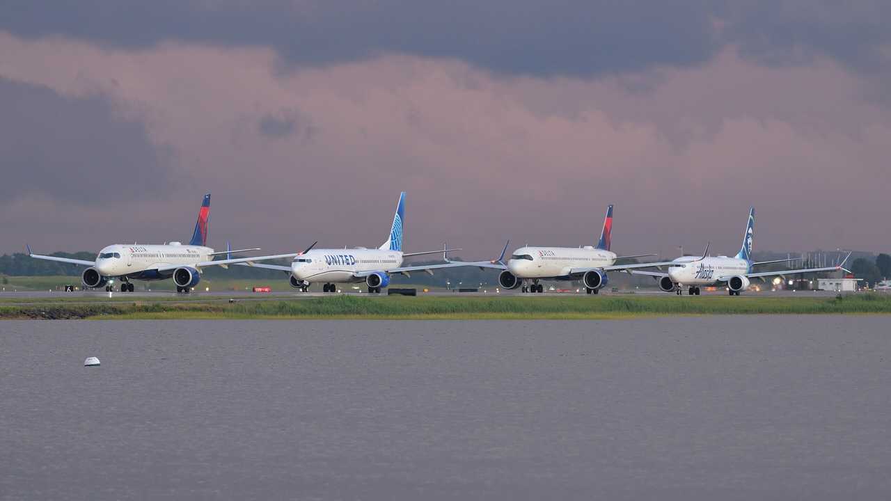 Several aircraft lined up on a taxiway at Boston Logan International Airport in July 2025.