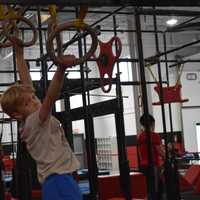 <p>A young client swings from ring to ring as part of their ninja training.&nbsp;</p>