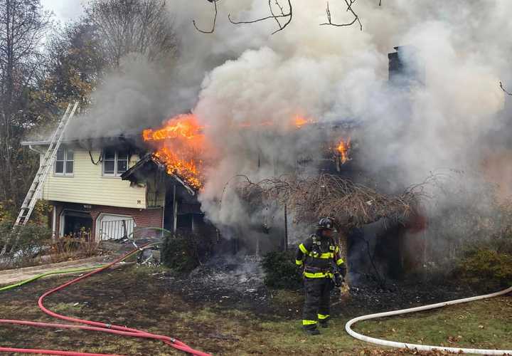 A firefighter stands in front of a two-alarm fire on&nbsp;Country Hills Road in Hamden on Sunday, Nov. 17.&nbsp;