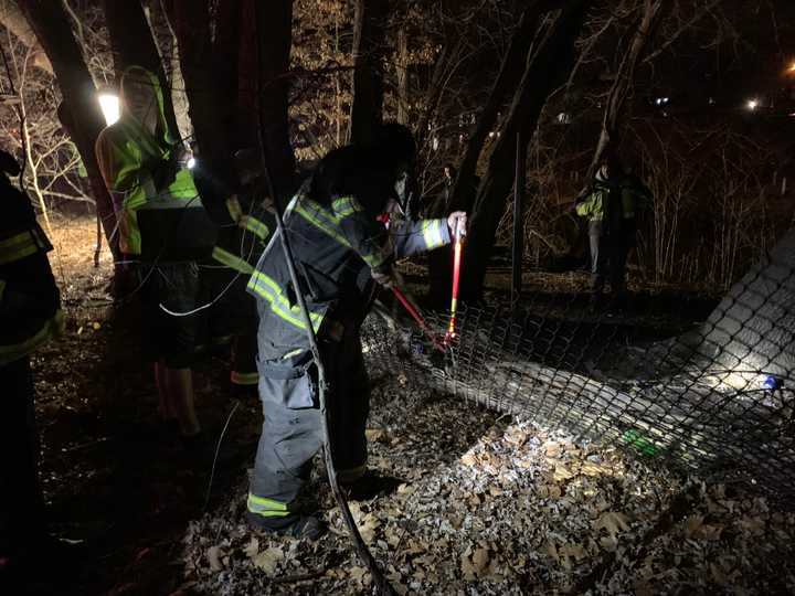 Firefighters cut through a metal fence to reach a fire in Somerville on Thursday, Dec. 19.&nbsp;