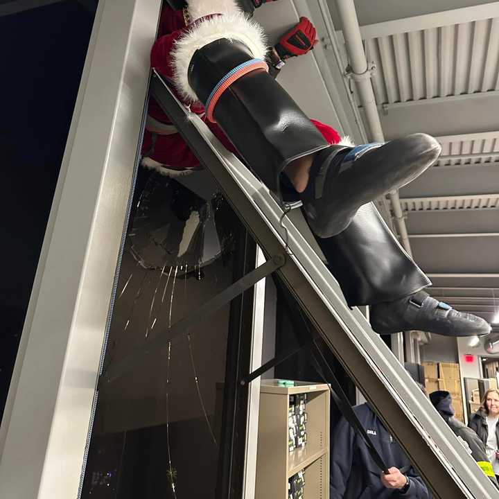 A performer dressed as Santa clings to the inside of a sixth-story window as firefighters pull him inside after his costume got stuck in his rigging as he rappelled down a building Saturday, Dec. 7, as part of the Norwalk Holiday Extravaganza.&nbsp;