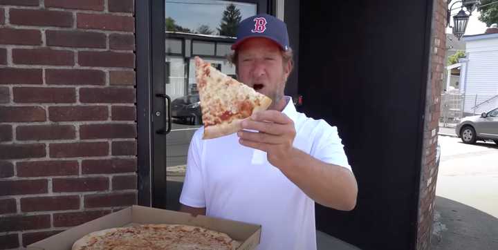 Dave Portnoy holds up a slice from Bravo Pizza in Quincy during a recent "One Bite Pizza Review."