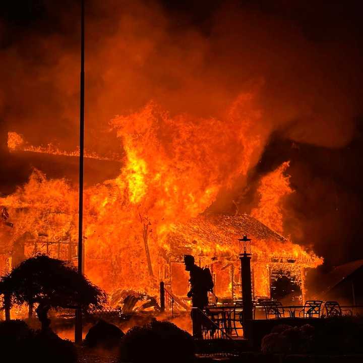 A firefighter is silhouetted in the glow of the roaring fire at Highland Golf Club in Shelton on Friday night, Nov. 15.